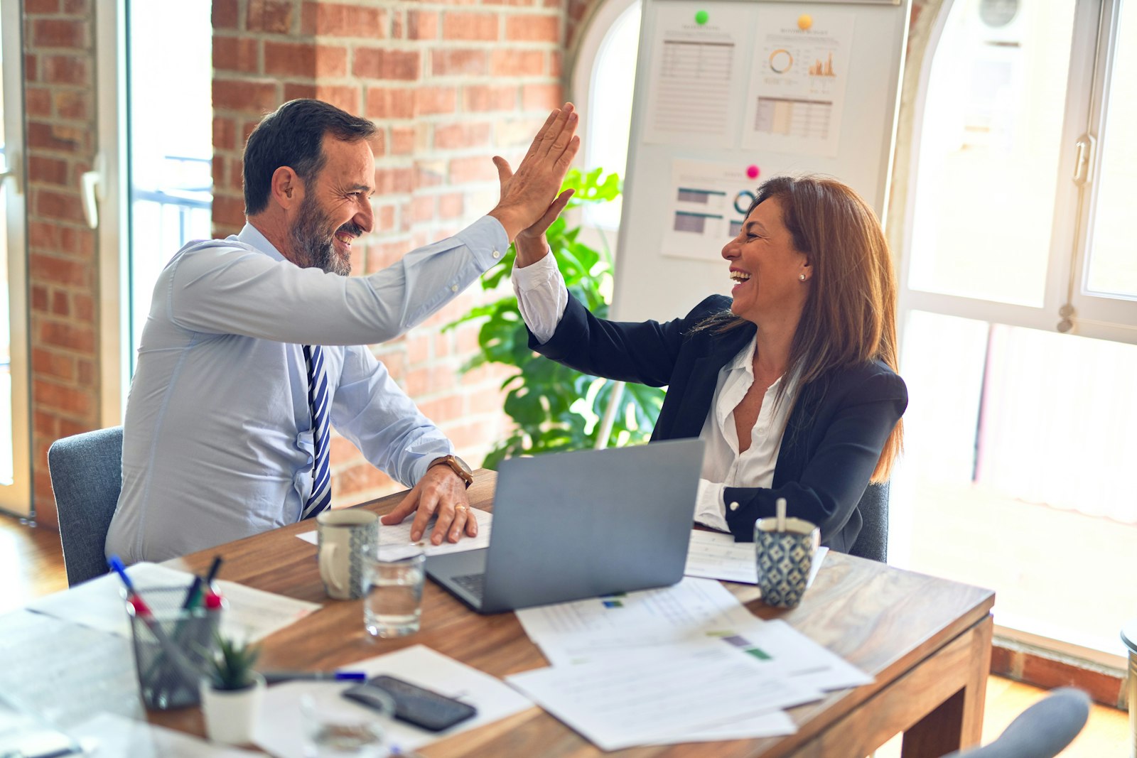 A manager and team member high-fiving in a one-to-one meeting